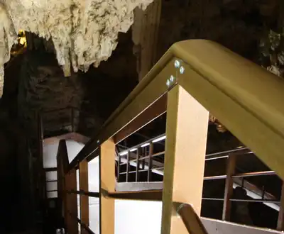 "Interior view of a cave with stalactites and wooden walkway structure, illuminated by soft lighting" [G]