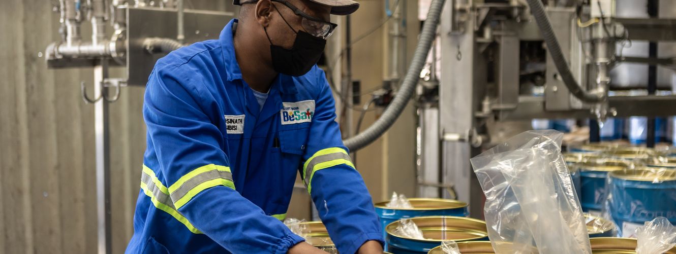 "Worker in blue uniform handling materials in Scott Bader manufacturing facility for resins and composites production" [G]