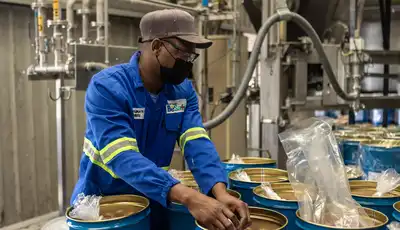 "Worker in blue uniform handling materials in Scott Bader manufacturing facility for resins and composites production" [G]