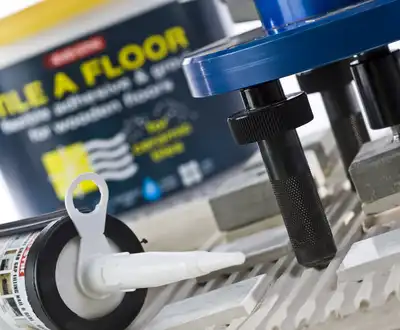 "Close-up of tiling tools and adhesive products for floor installation, showcasing Scott Bader structural adhesives for construction applications." [G]