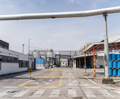 "Industrial manufacturing facility with storage drums and pipelines at Scott Bader's chemical production site for resins and composites" [G]