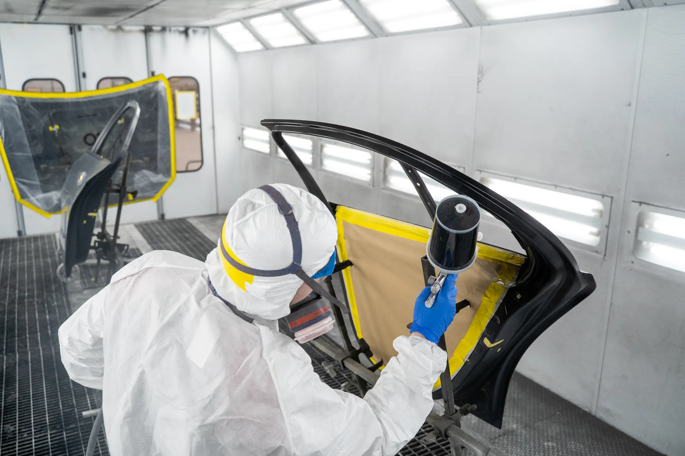 "Technician applying Scott Bader gelcoats to automotive door panel in spray booth, showcasing precision composite application" [G]