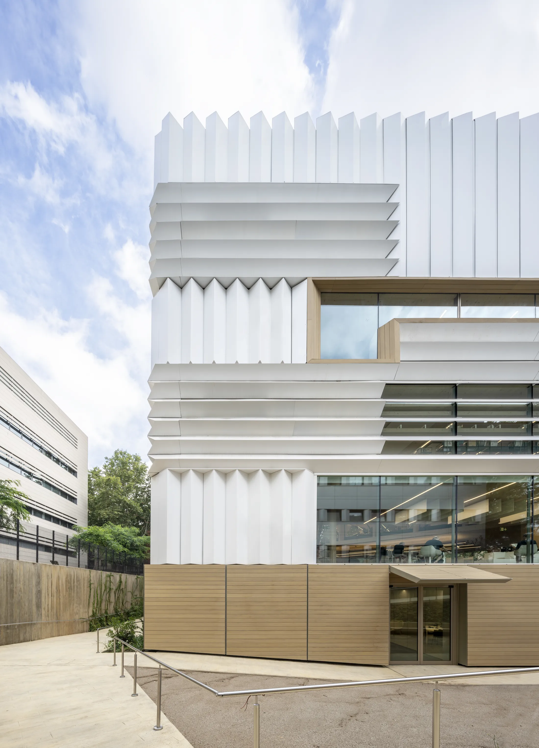 Modern architectural building with distinctive white composite panels and wooden elements under blue sky [G]