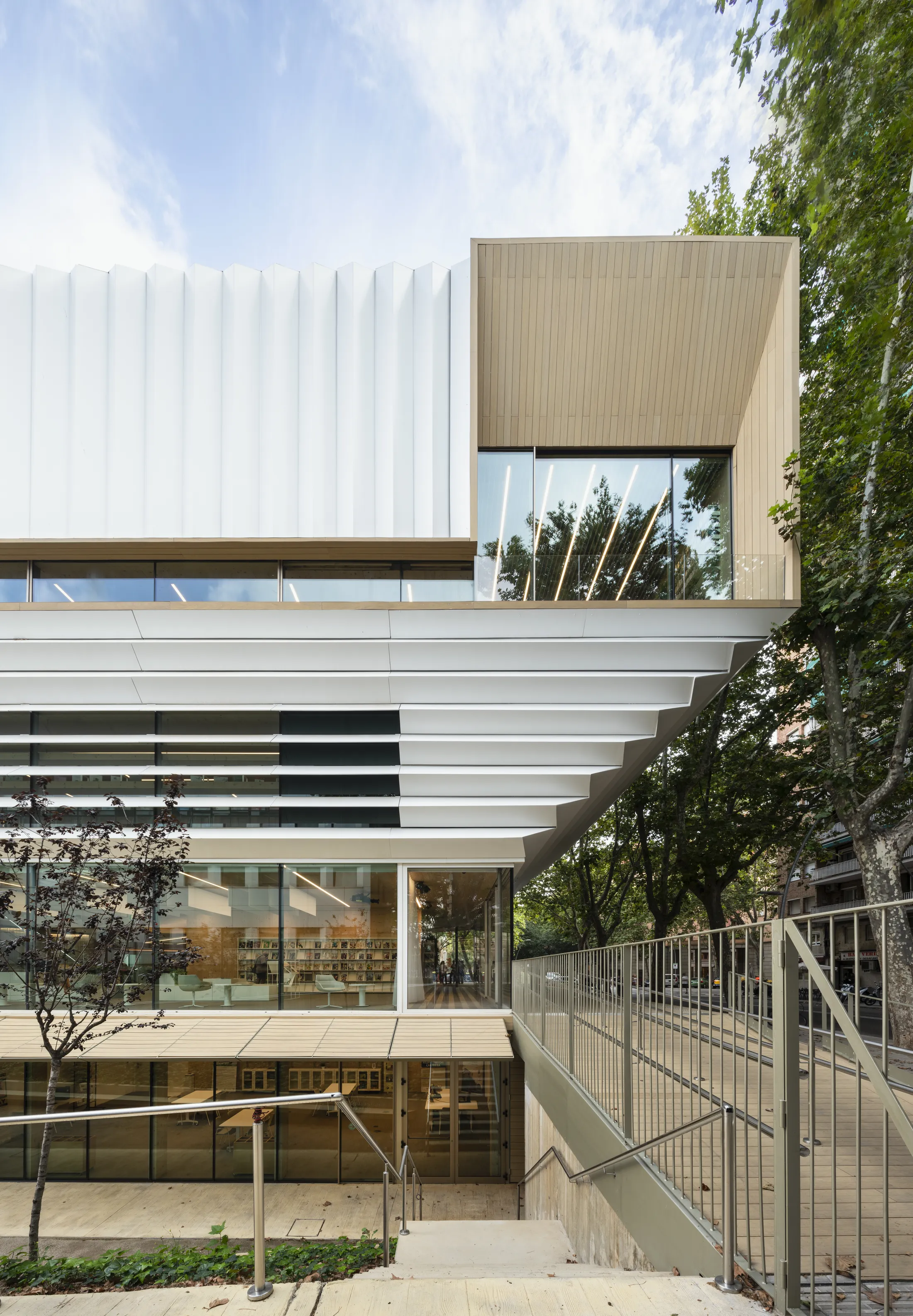 "Modern architectural building with white composite panels and glass elements surrounded by greenery" [G]