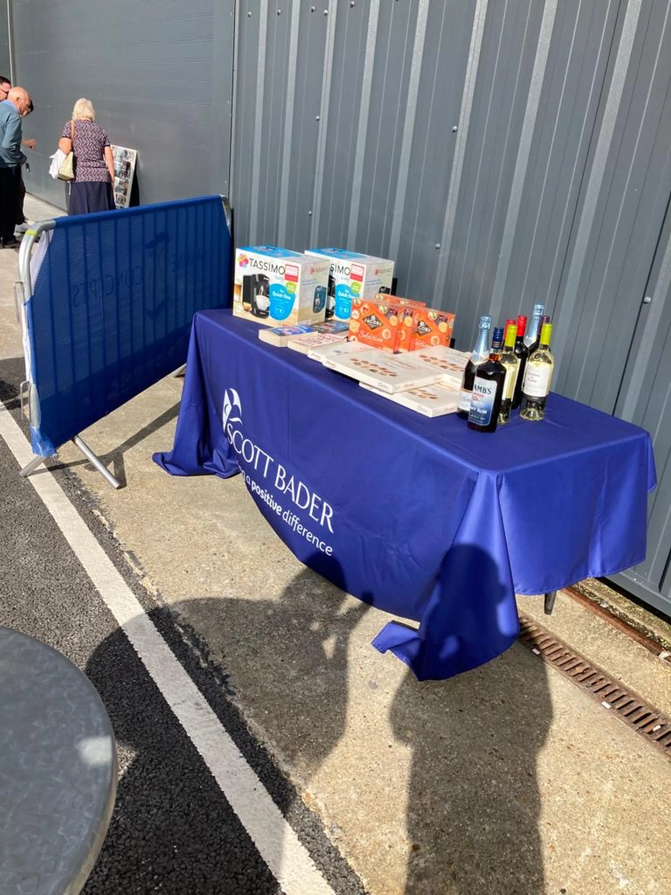 "Scott Bader exhibition table with refreshments and promotional materials at industry conference" [G]