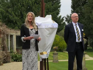 "Outdoor ceremony with speakers and covered display in garden setting at Scott Bader event" [G]