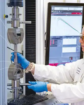"Laboratory technician in protective gear testing materials at Scott Bader's facility for quality control of resins and composites" [G]