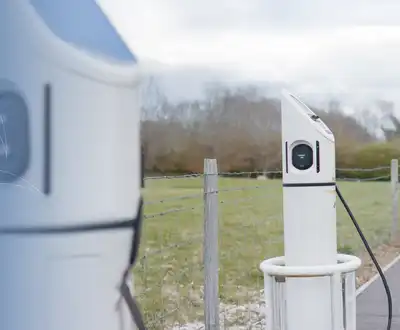 "Electric vehicle charging station with white charging units and blue car - Scott Bader composites for sustainable transportation infrastructure" [G]
