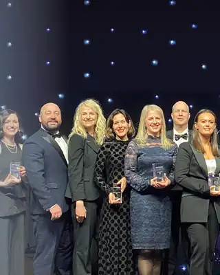 "Award ceremony with recipients holding trophies on stage against a starry backdrop, representing Scott Bader's industry recognition" [G]