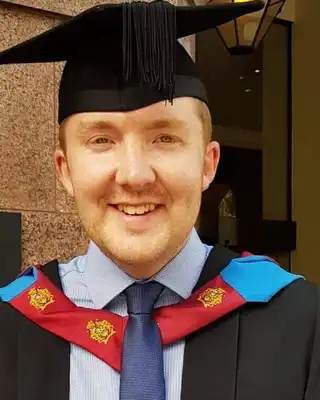 "Graduate in academic regalia with black cap and colorful hood celebrating achievement at university ceremony" [G]