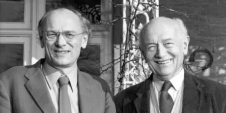 "Historic black and white photograph of two smiling executives outside a building, representing Scott Bader's leadership in composites and resins" [G]