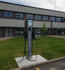 "Electric vehicle charging station outside Scott Bader office building with grassy area and brick facade" [G]