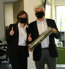 "Scott Bader professionals in masks giving thumbs up, one holding metallic equipment possibly for adhesives or resins application" [G]