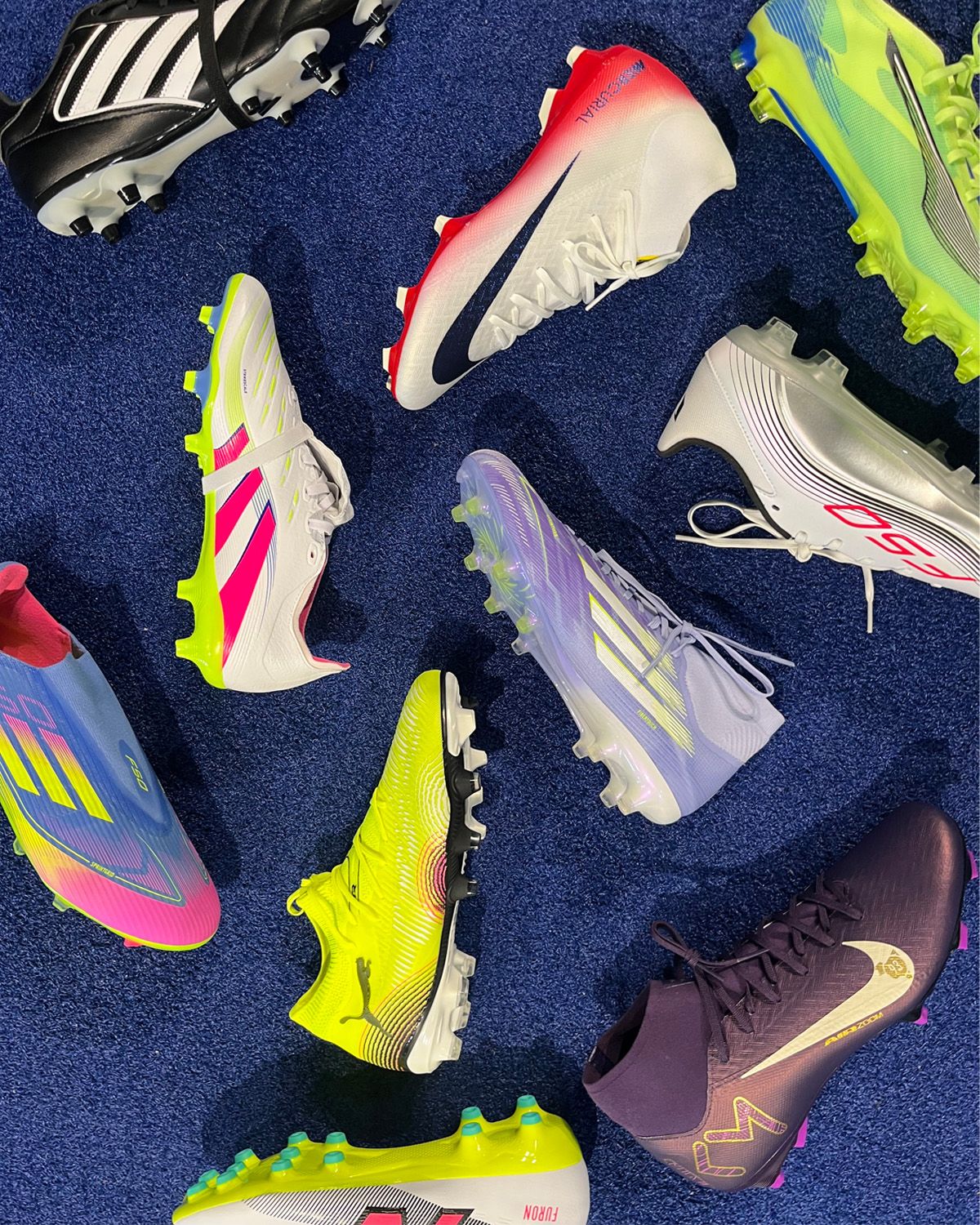 Various colorful soccer cleats arranged on a blue surface, showcasing different brands and designs.