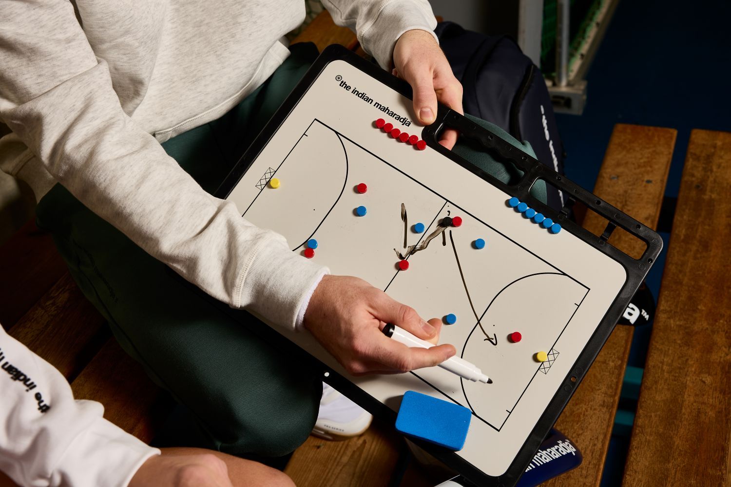Person holding a tactics board with colored magnets, demonstrating hockey strategy with a marker.