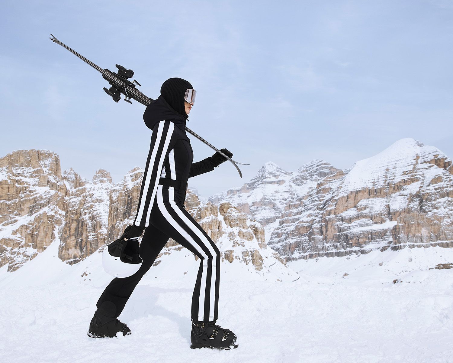 Vrouw in zwart met witte strepen skipak in de besneeuwde bergen.