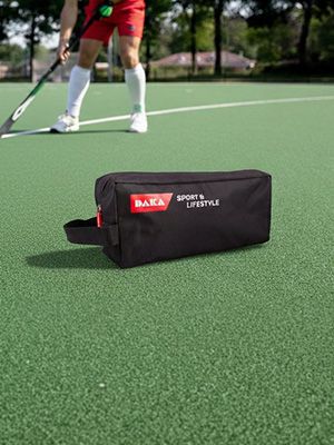 Black sports bag on a green field with a hockey player in the background.