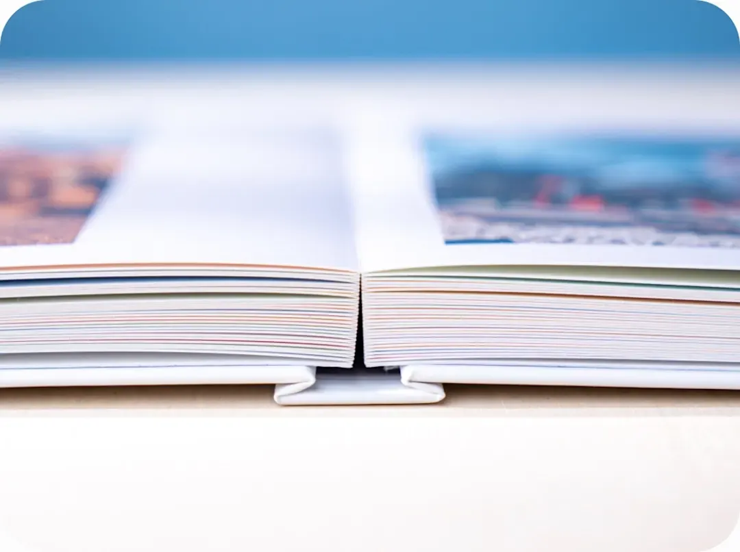 Close-up of an open book lying flat, showing colorful page edges against a blurred blue background.