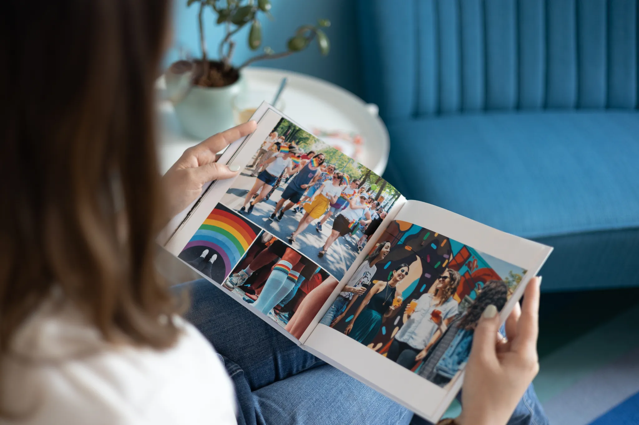 Eine Frau hält ein Fotobuch mit Fotos einer Gruppe junger Menschen auf einer Pride-Veranstaltung.