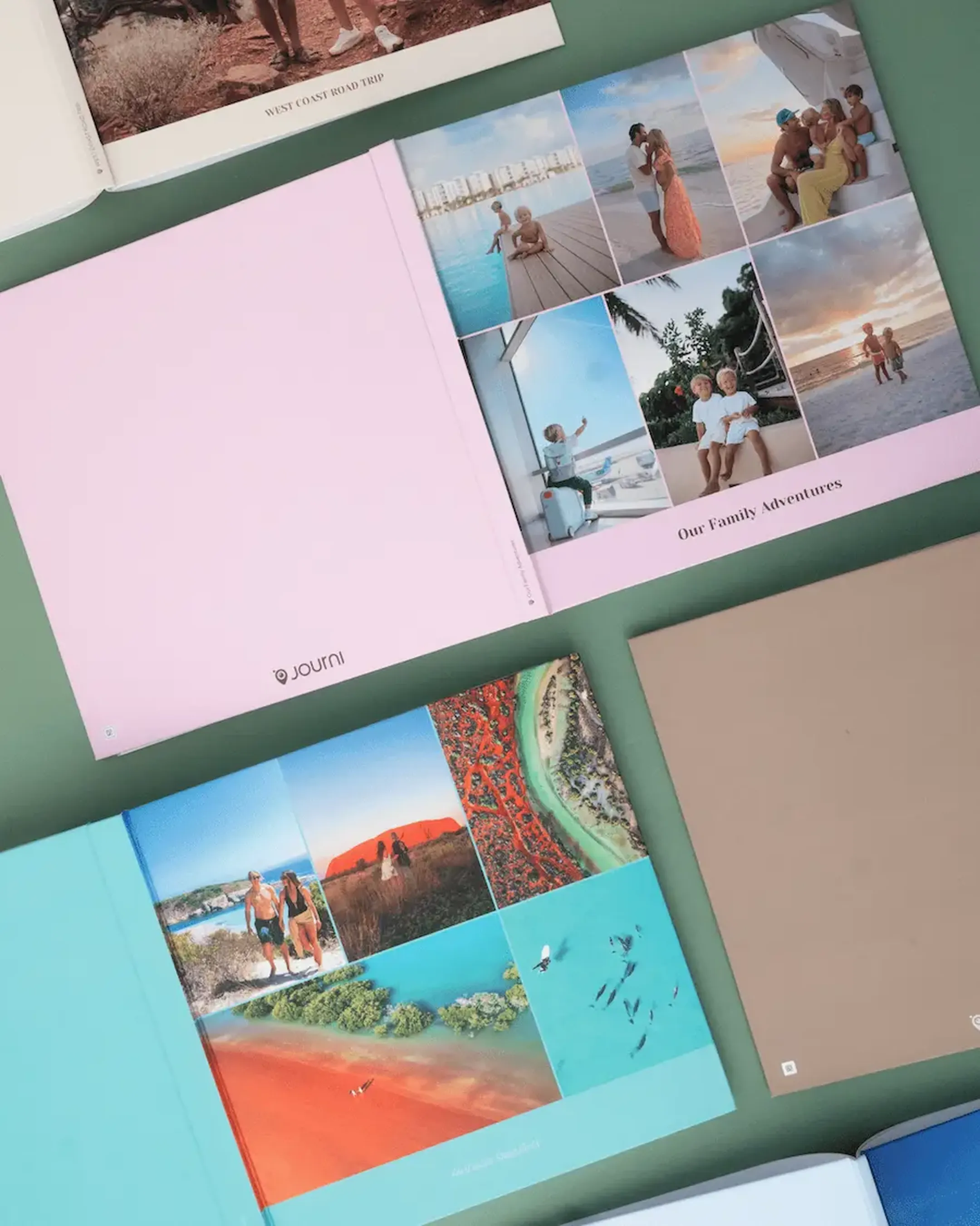 Photo books laid out on a green surface, showcasing various family and travel photos in colorful covers.
