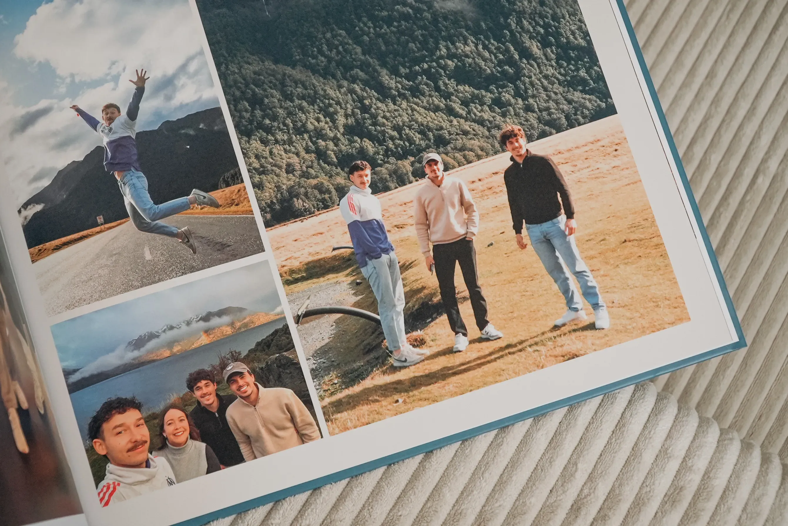Open photo book with images of friends outdoors: one jumping joyfully, group posing by a mountain and lake, and smiling selfies.