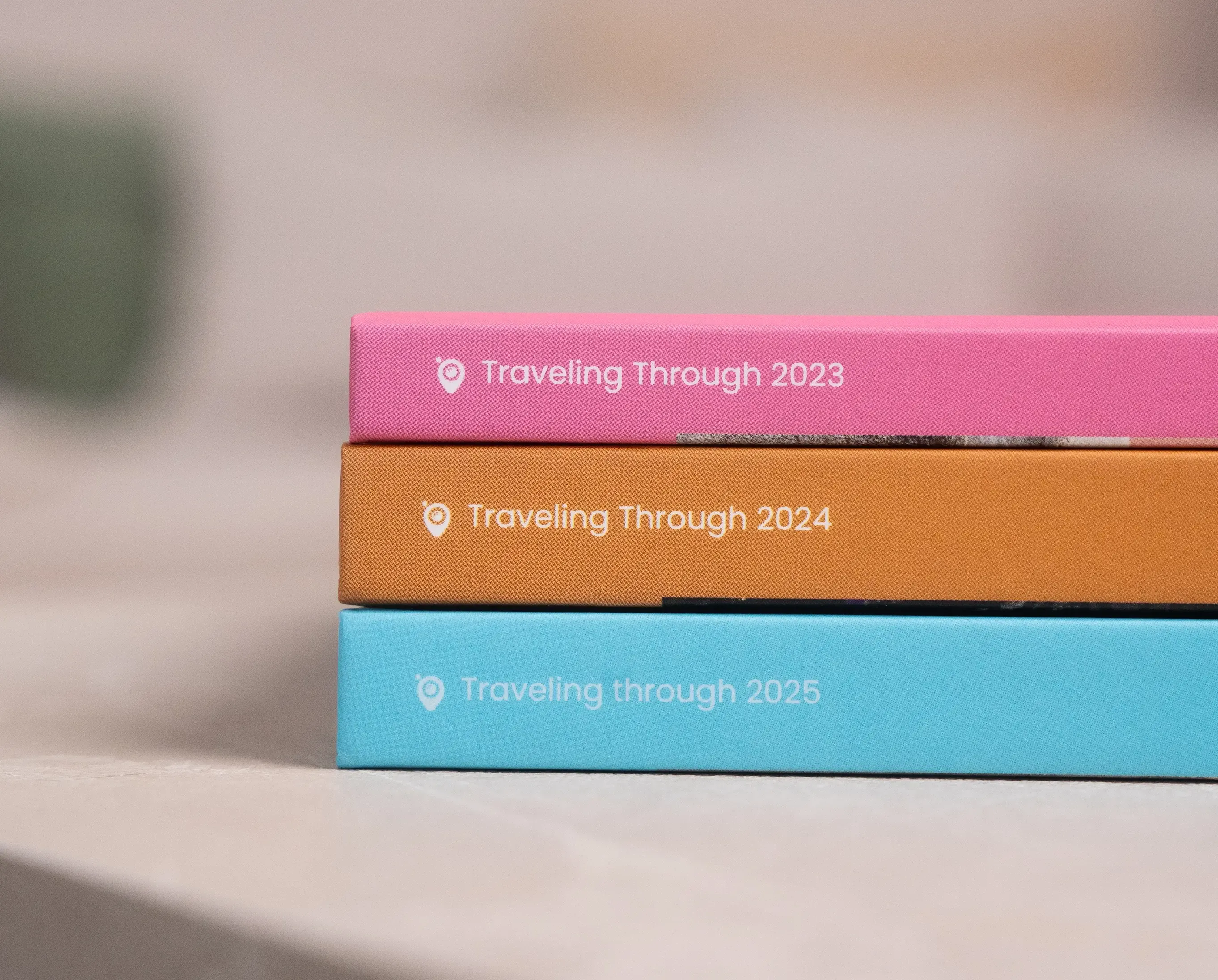 Drei bunte Kisten (rosa, orange, blau) mit den Aufschriften „Reise durch 2023”, „Reise durch 2024” und „Reise durch 2025”.