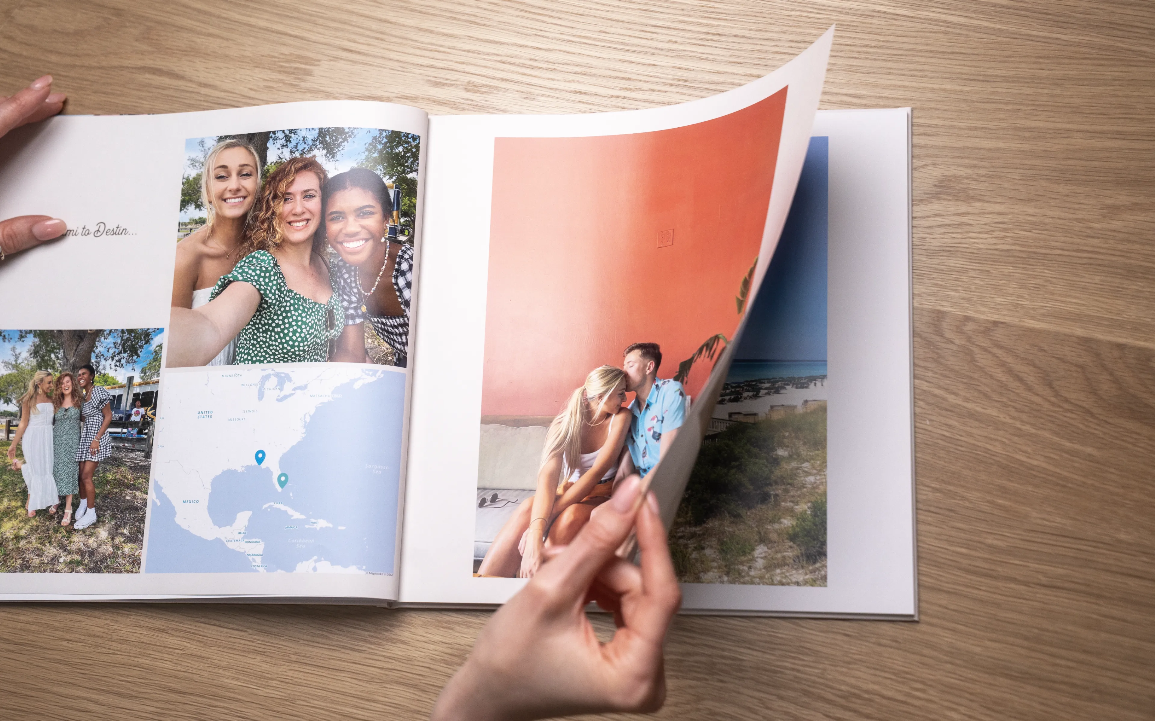 Hands flipping through a photo album on a wooden surface, showing pictures of friends, a map, and a couple on a beach.