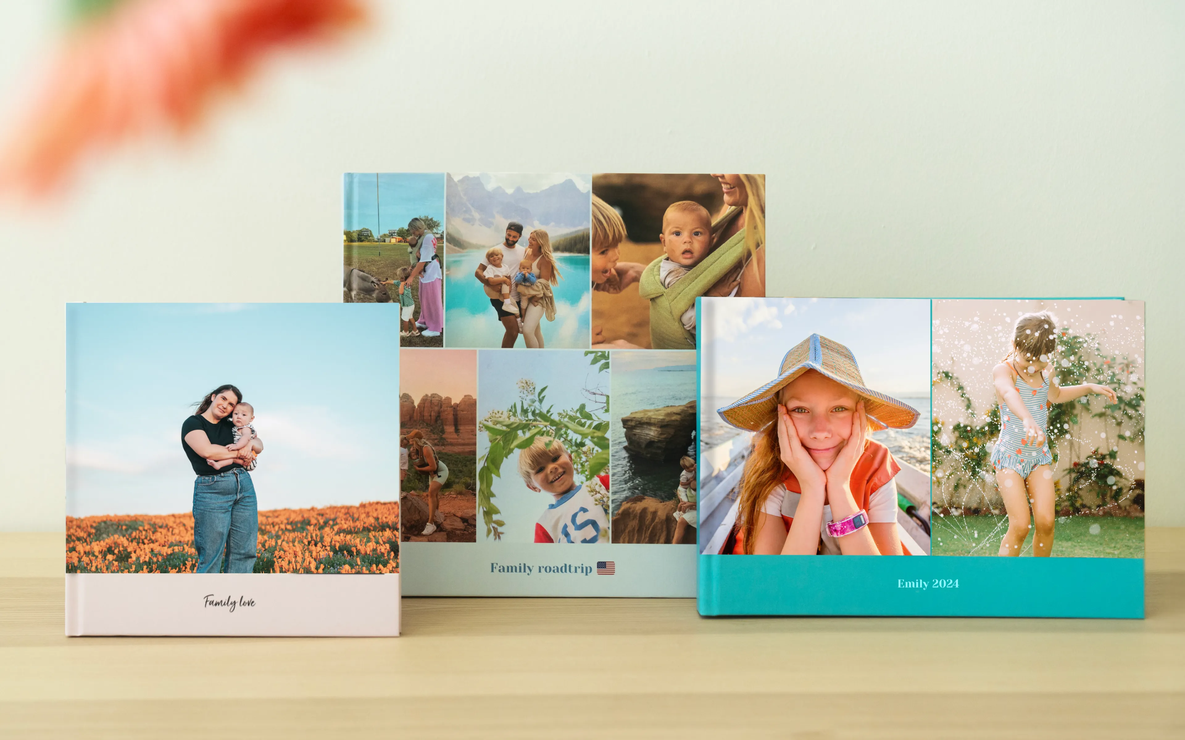 Drei bunte Familienfotoalben stehen auf einem Tisch, und auf jedem Cover sind verschiedene Familienmomente und Outdoor-Szenen zu sehen.