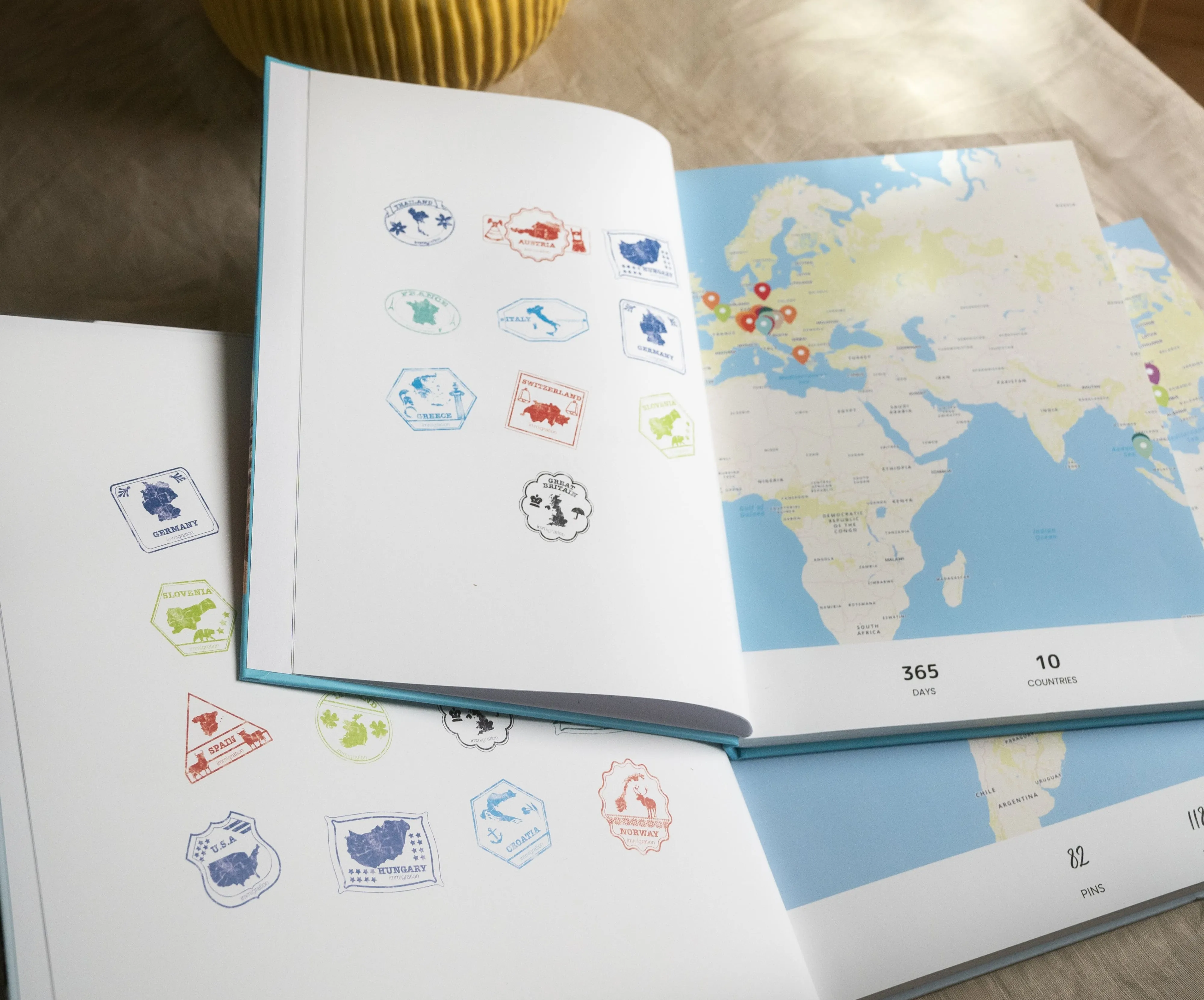 Open travel journal with stamped pages and a world map, showing various locations marked with pins.
