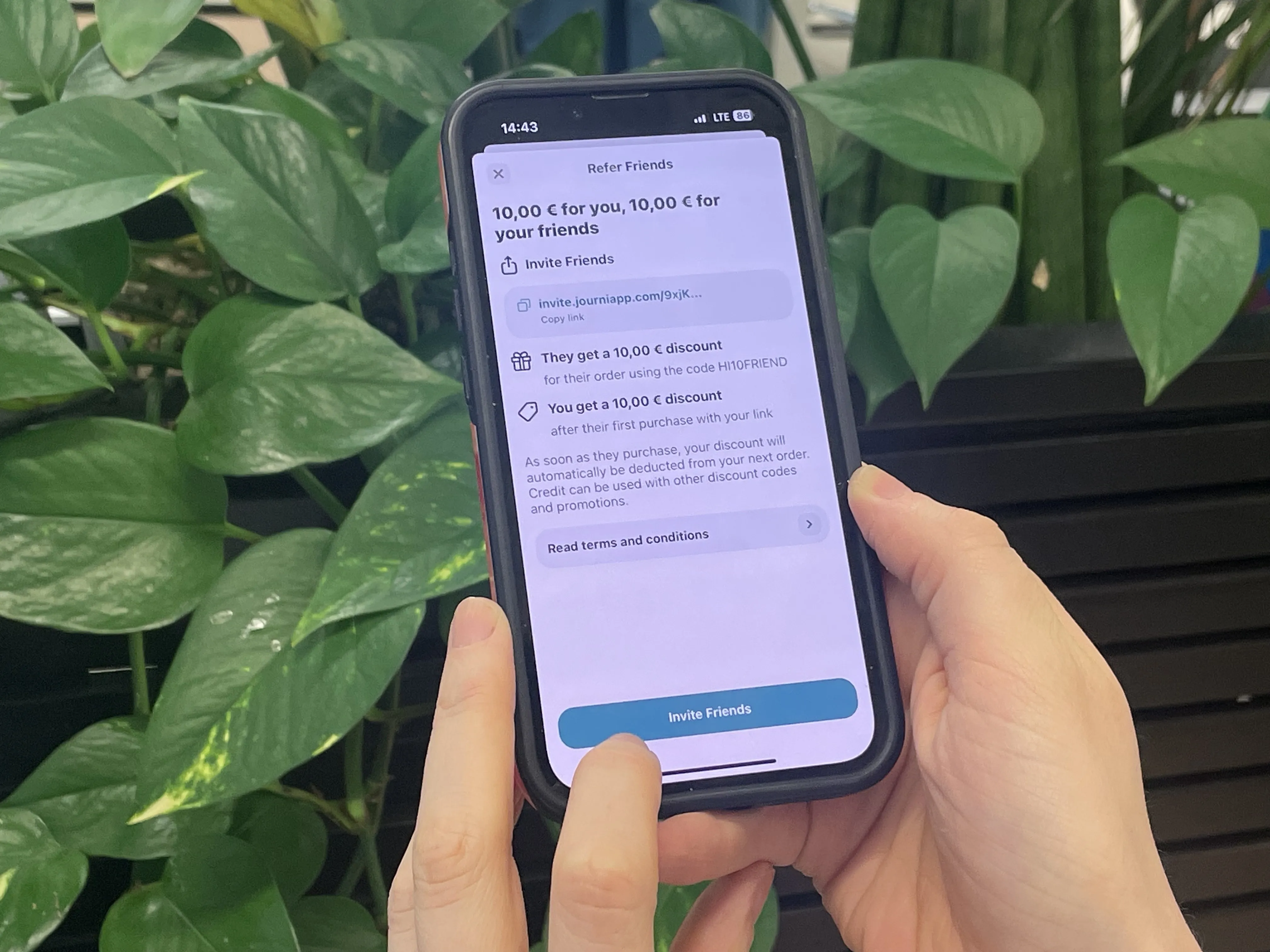 a person holding a phone in their hands reading about the Journi referral discount