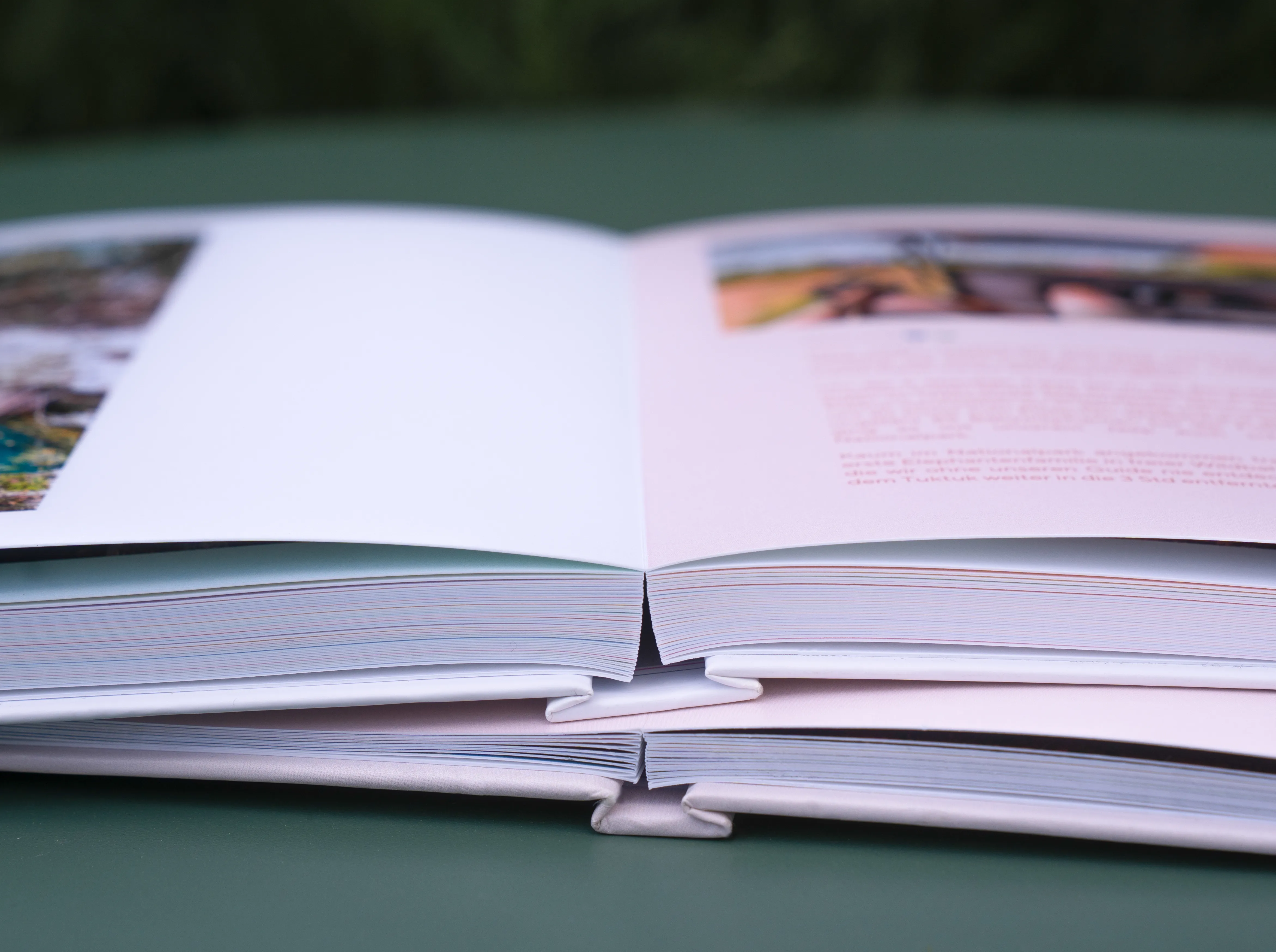Detailaufnahme zweier offener Fotobücher mit Layflat-Bindung mit Fotos und Text.