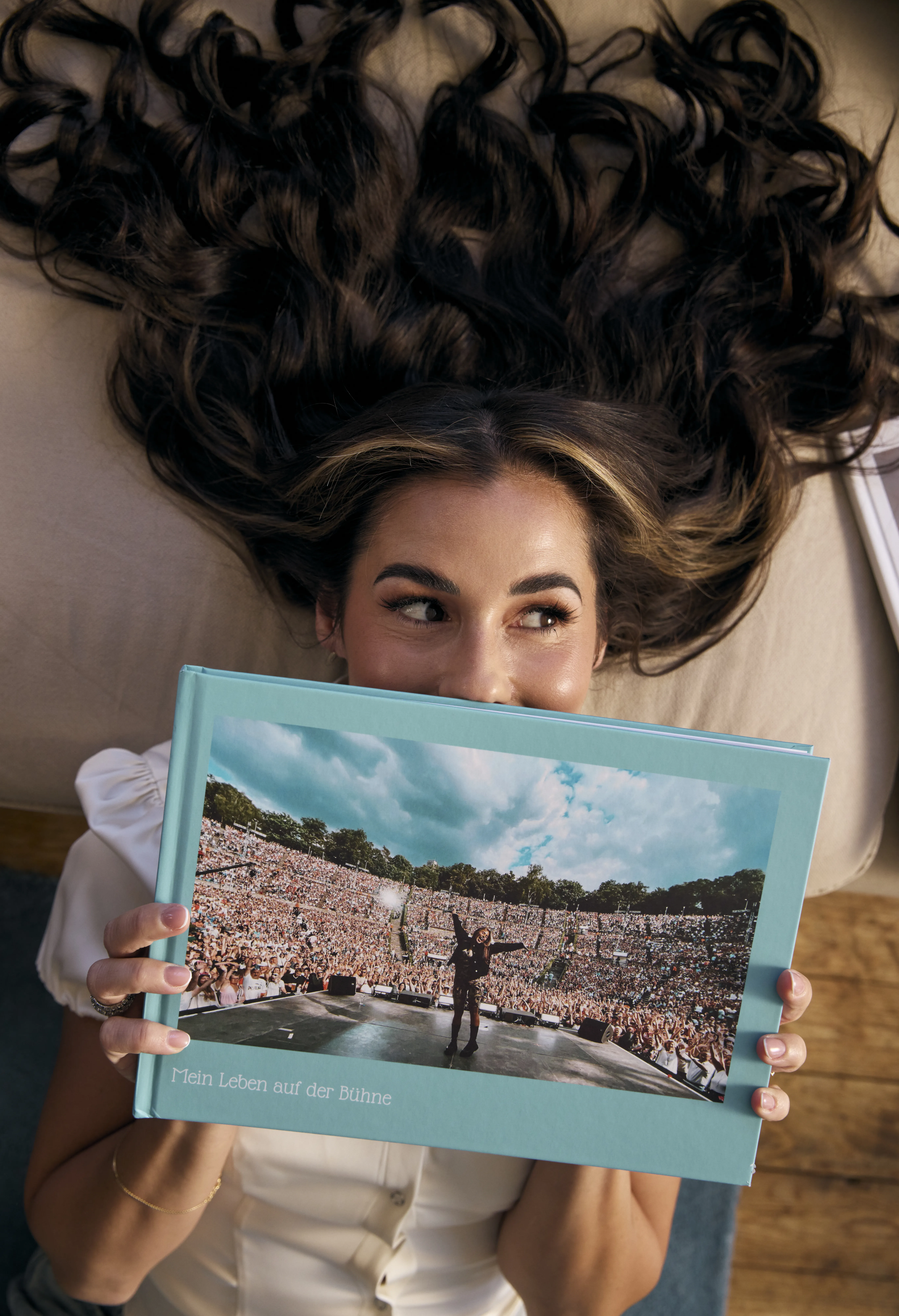 Sarah Engels liegt auf einer Couch mit einem Fotobuch ihrer Tour vor dem Gesicht.