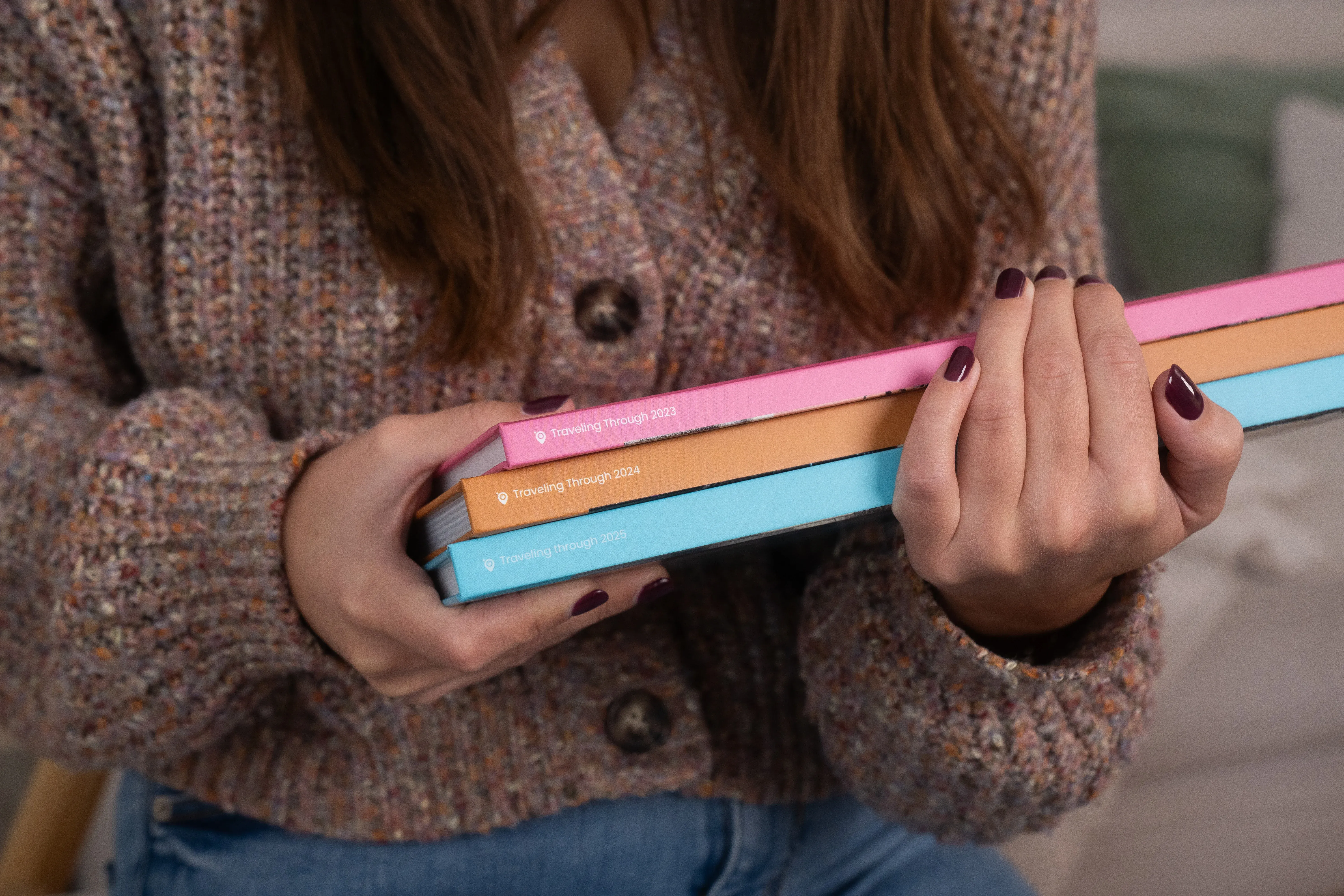 Frau trägt unterschiedliche Fotobücher mit bunten Buchrücken.