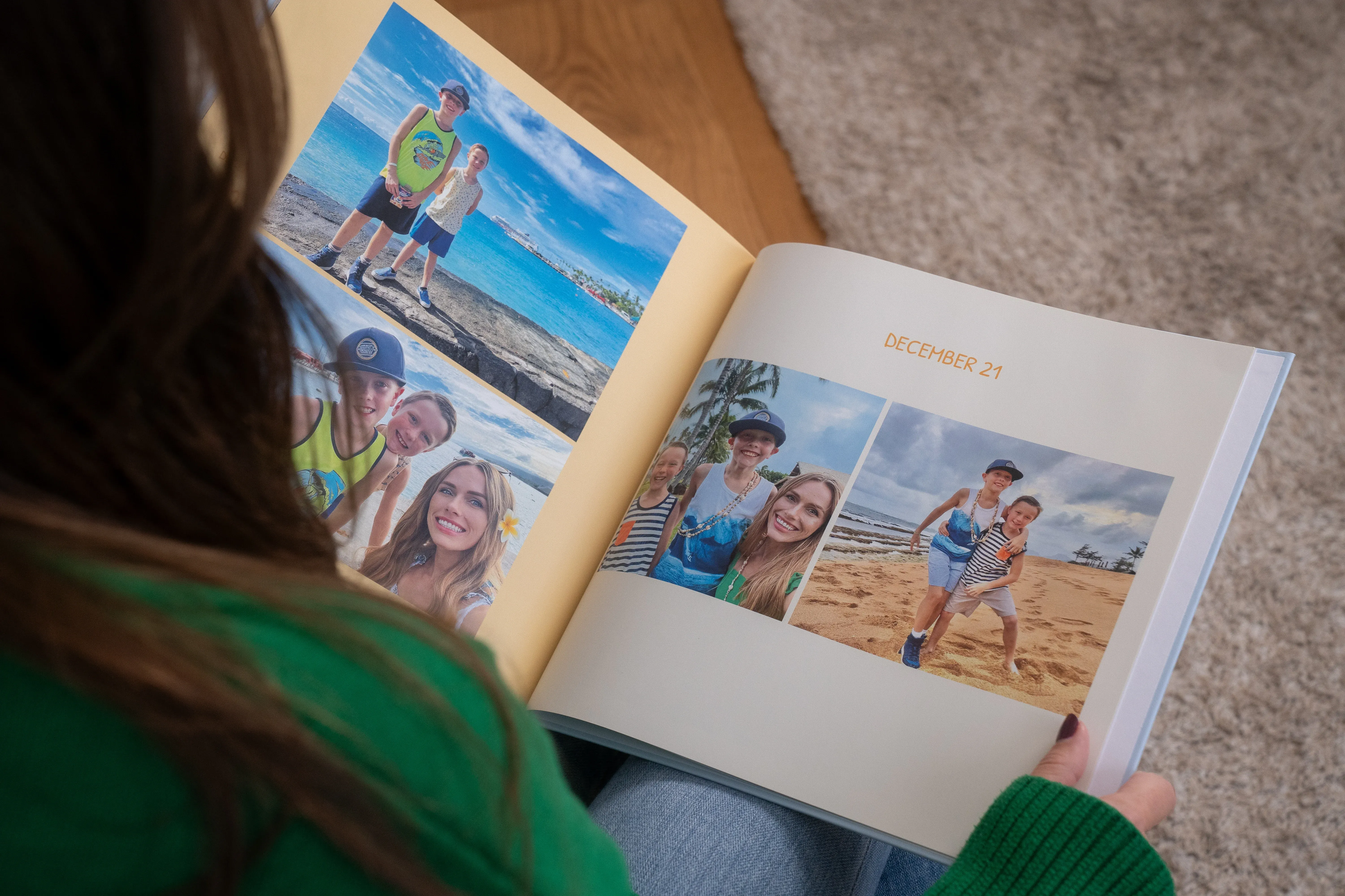 Person holding an open photo album showing beach vacation photos with family and "December '21" written on the page.
