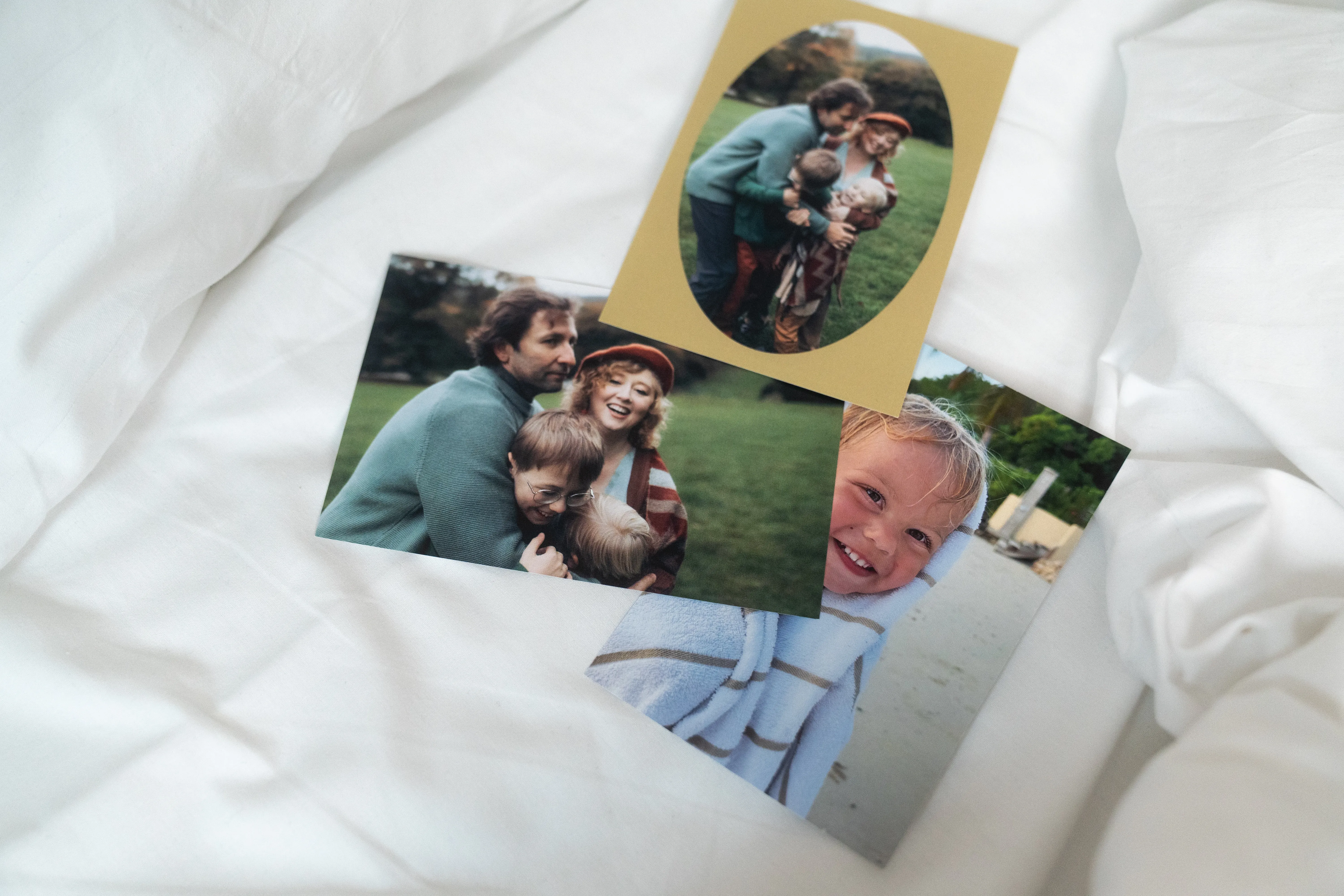Tres fotos familiares sobre tela blanca: dos adultos con un niño en el parque y un niño sonriendo en la playa envuelto en una toalla.