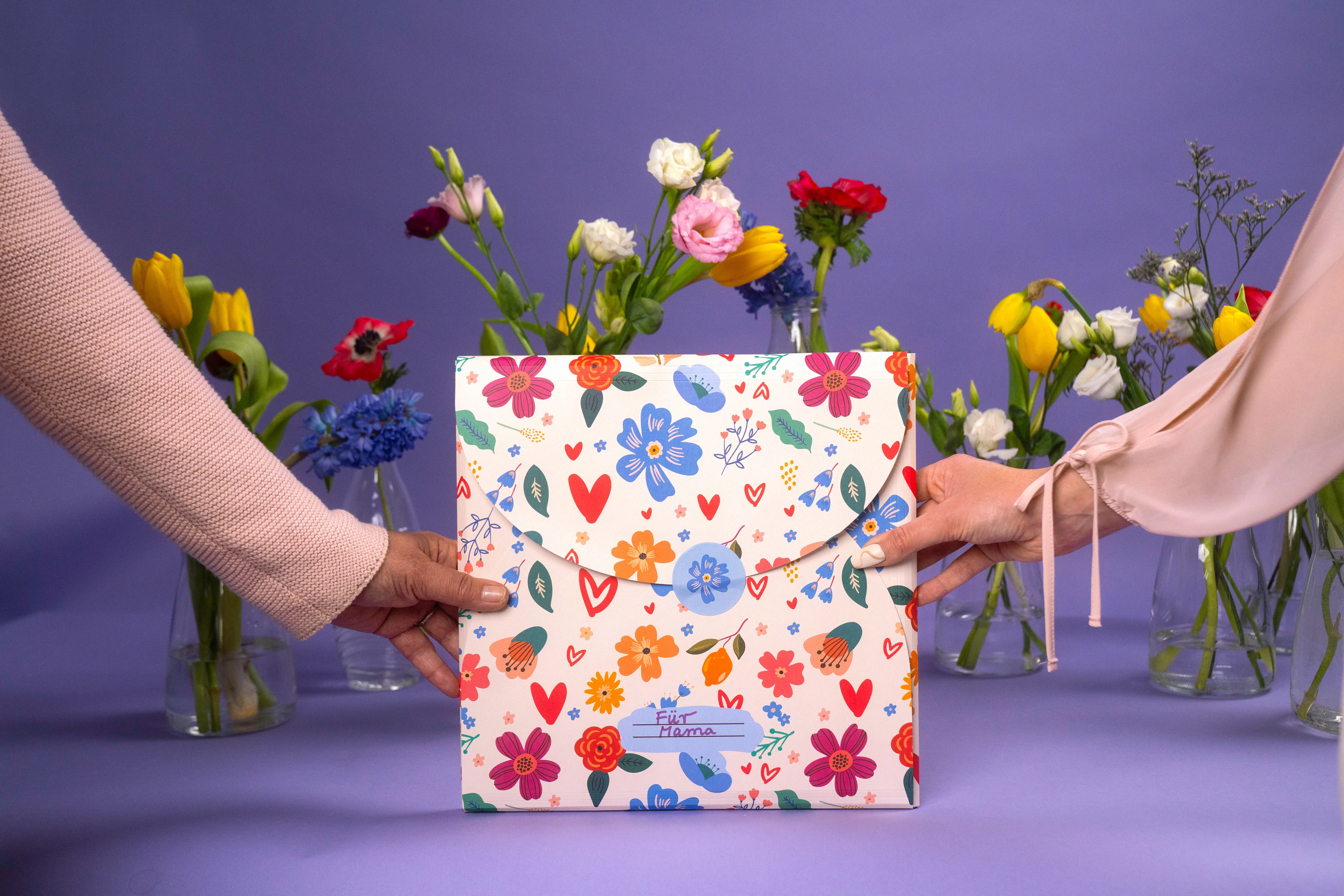 two hands holding a gift wrapped in journi heart print wrapping paper