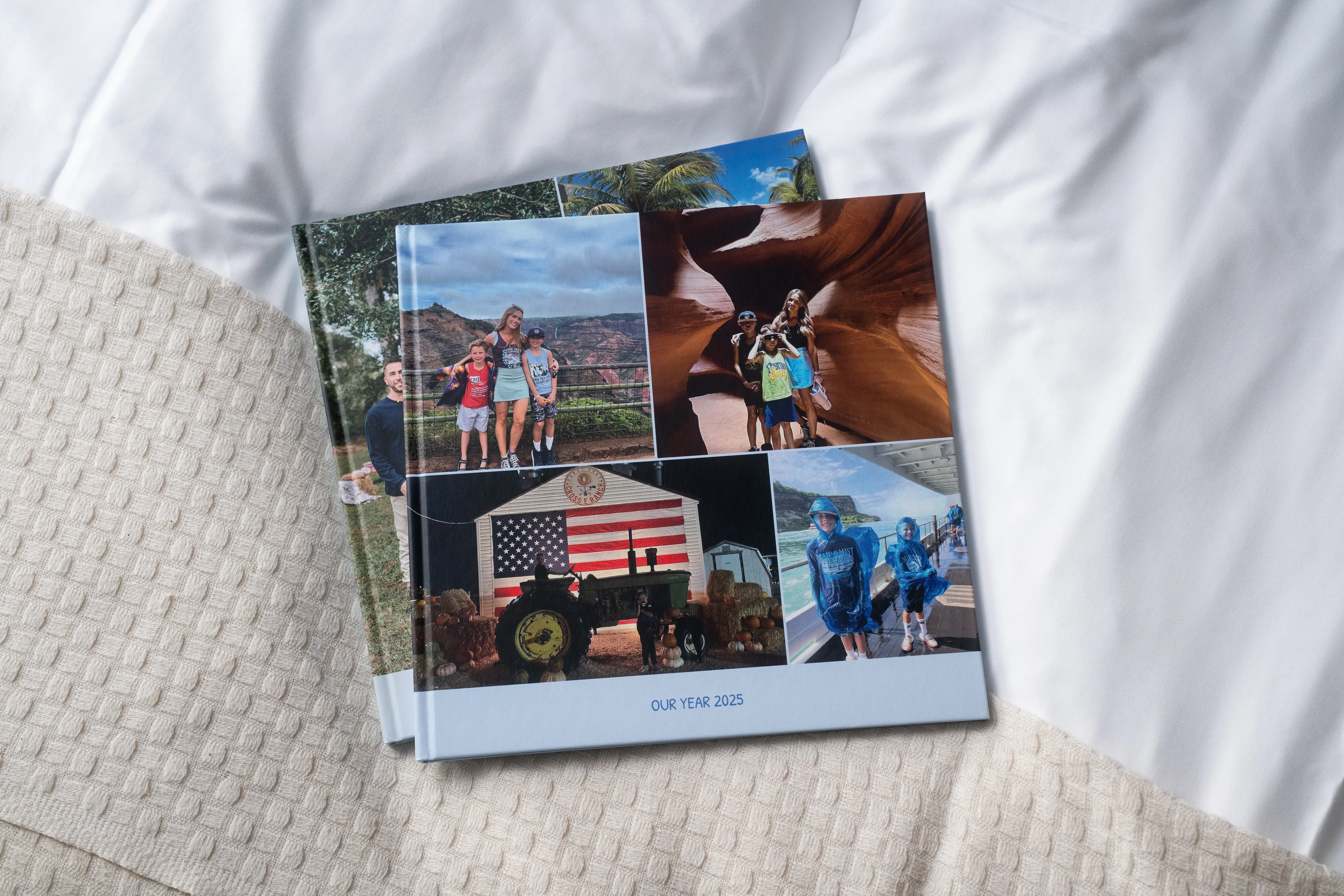 Zwei Fotobücher mit einer Collage aus Familienurlaubsfotos auf dem Cover. Der Text lautet „Unsere Reise 2023“.