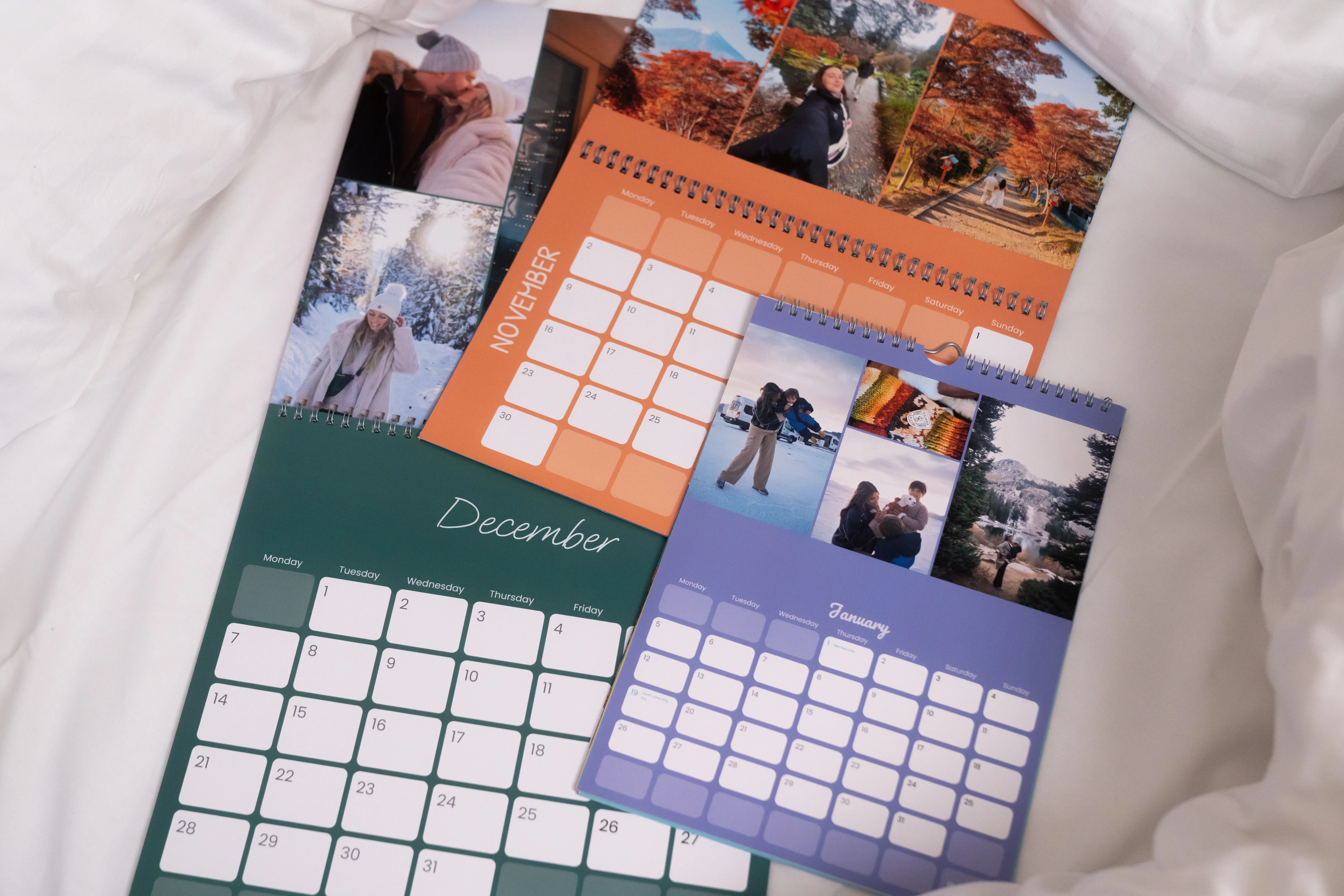 Drei Fotokalender in unterschiedlichen Formaten und Farben auf einem weißen Hintergrund.