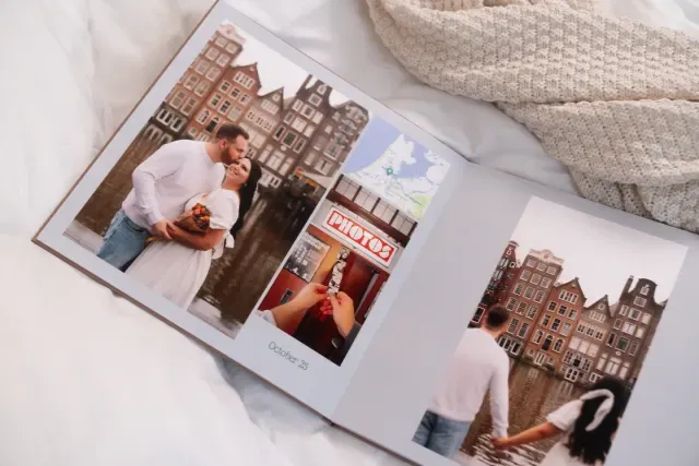 Open photo album with images of a couple in front of traditional buildings, a photo booth, and a person holding an apple, dated "October 25."