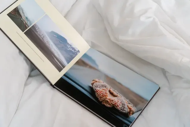 Offenes Layflat-Fotobuch auf einem Bett mit Fotos einer Reise im Winter.