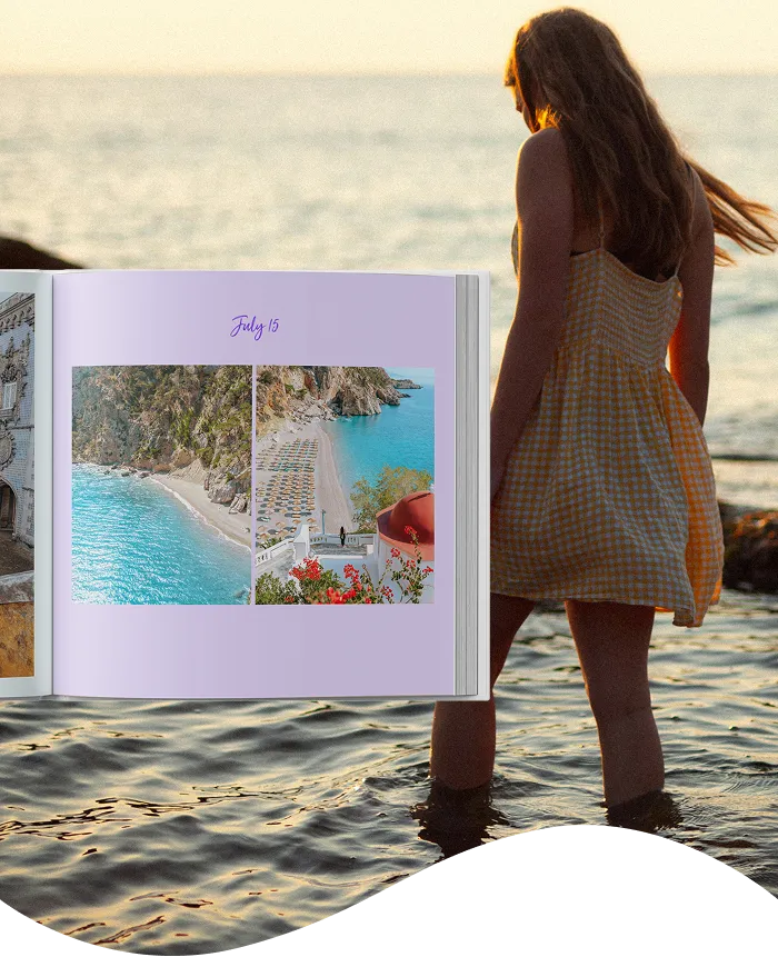 A girl in a yellow dress stands in shallow sea water at sunset, beside an open photo album showing beach images dated July 15.