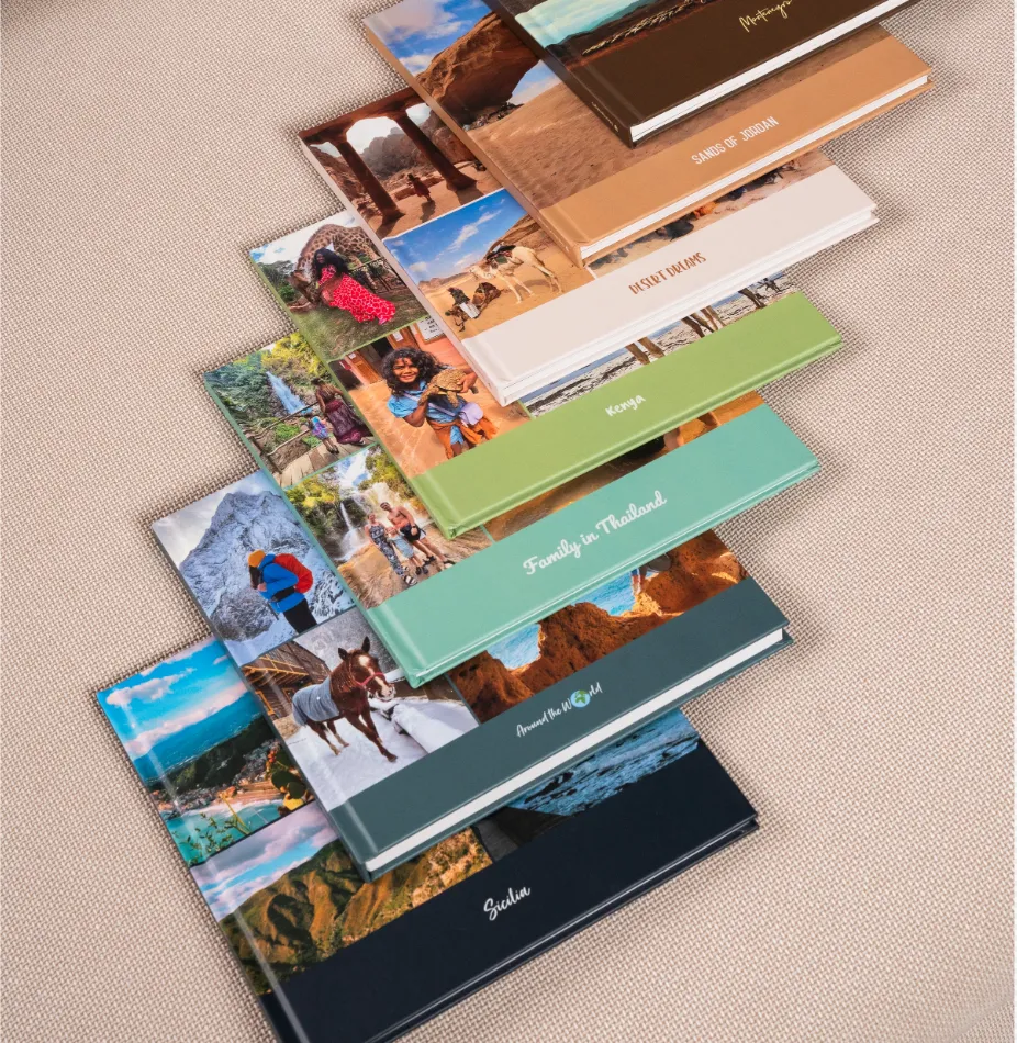 Mehrere Hardcover-Fotobücher auf einer beigen Couch mit unterschiedlichen Titeln und Fotos von Reisen.
