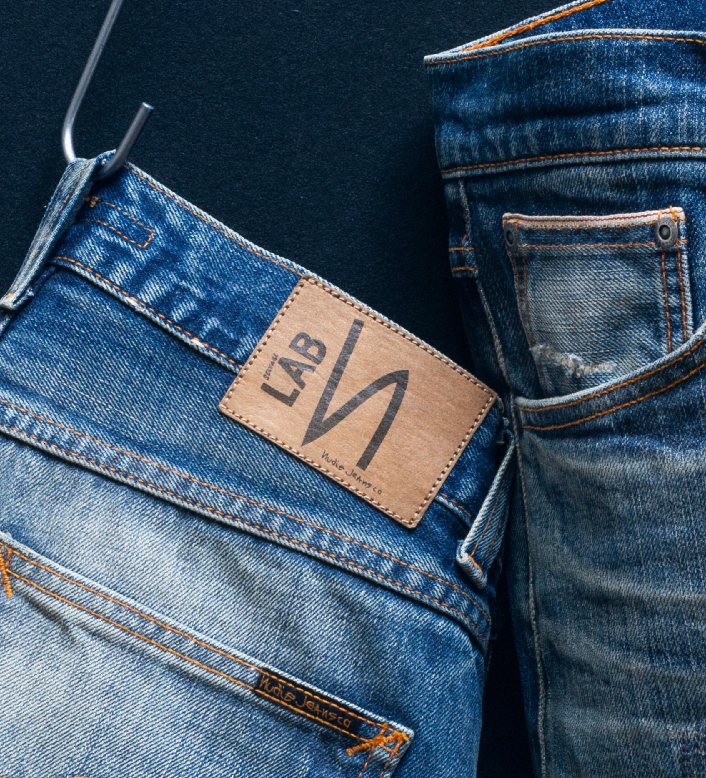 Close-up of two pairs of blue jeans with visible stitching and a leather label reading "Selvage LAB"