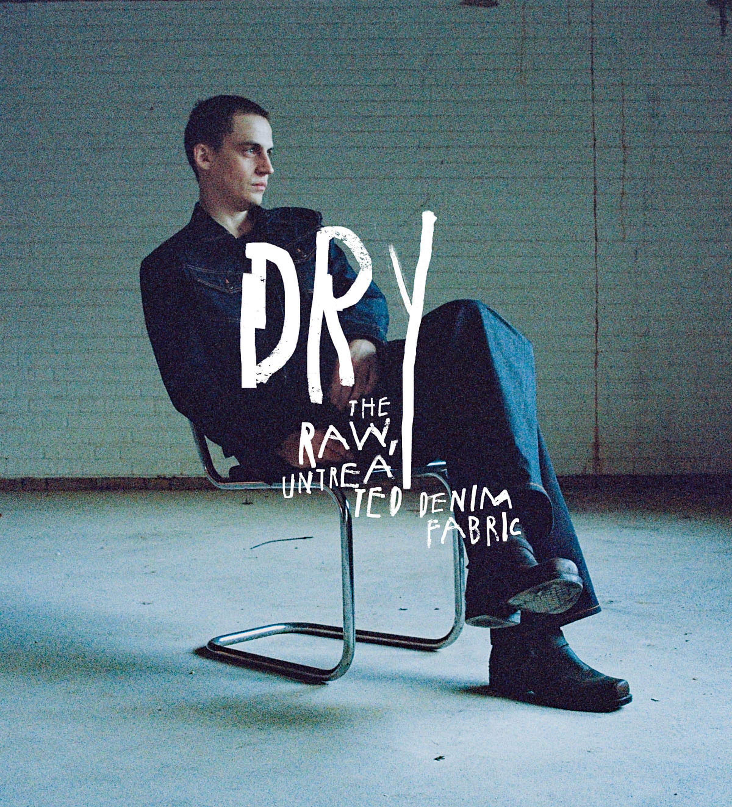 Person seated on a metal chair in a dimly lit room, wearing dark clothing. Text overlay reads "DRY: The Raw, Untreated Denim Fabric."