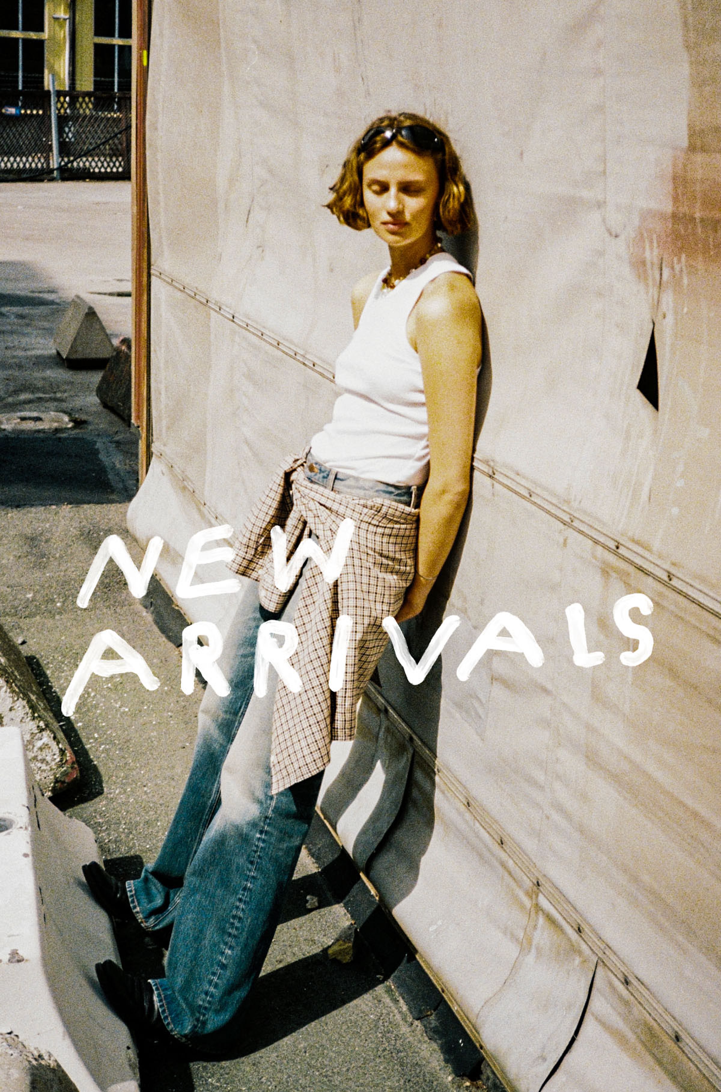 Women in a pair of Nudie jeans leans against a wall with "New Arrivals" text overlay.