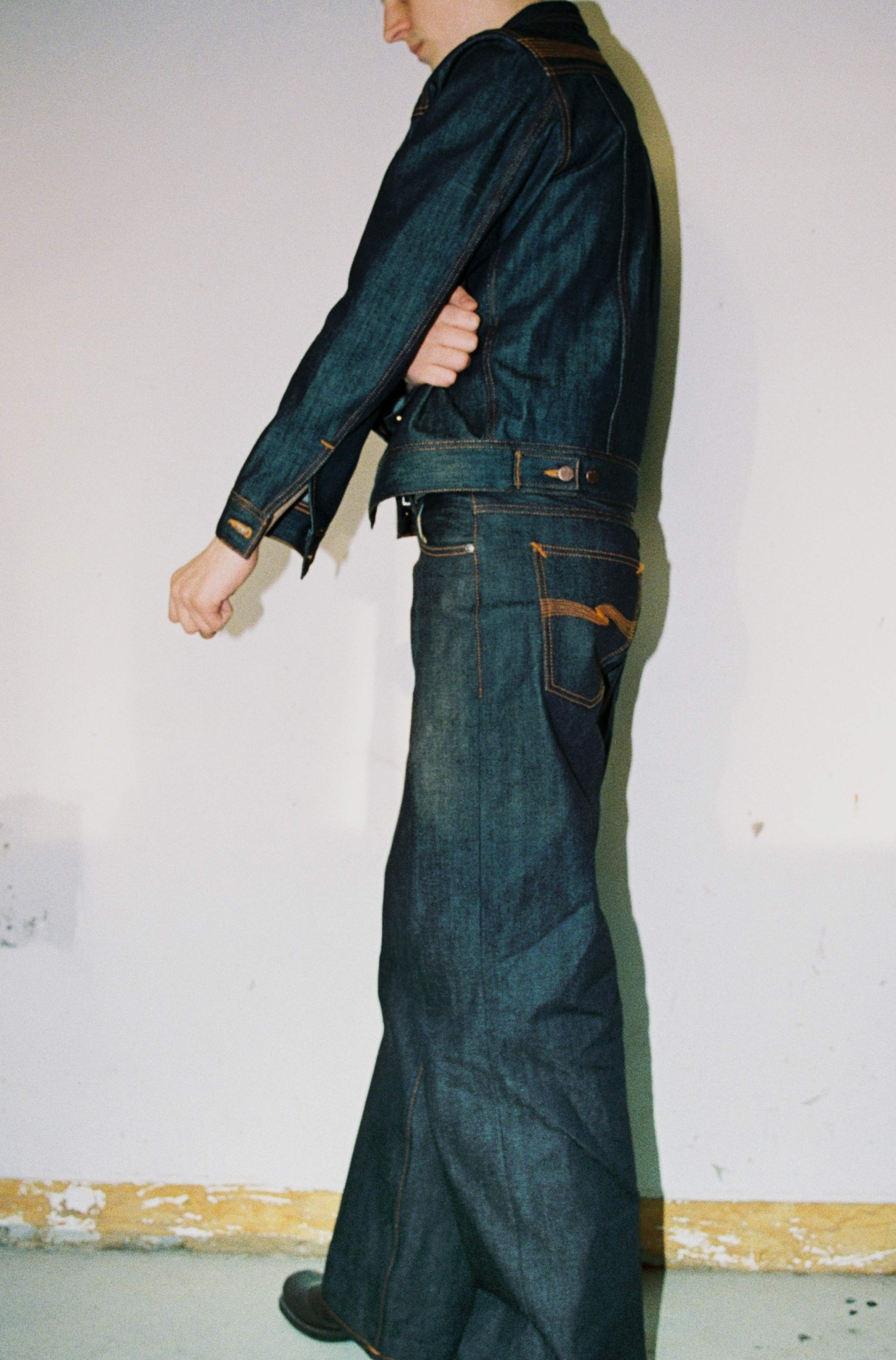 Side view of model wearing Nudie Jeans Kaihara dry raw selvedge denim jacket and matching wide-leg jeans.