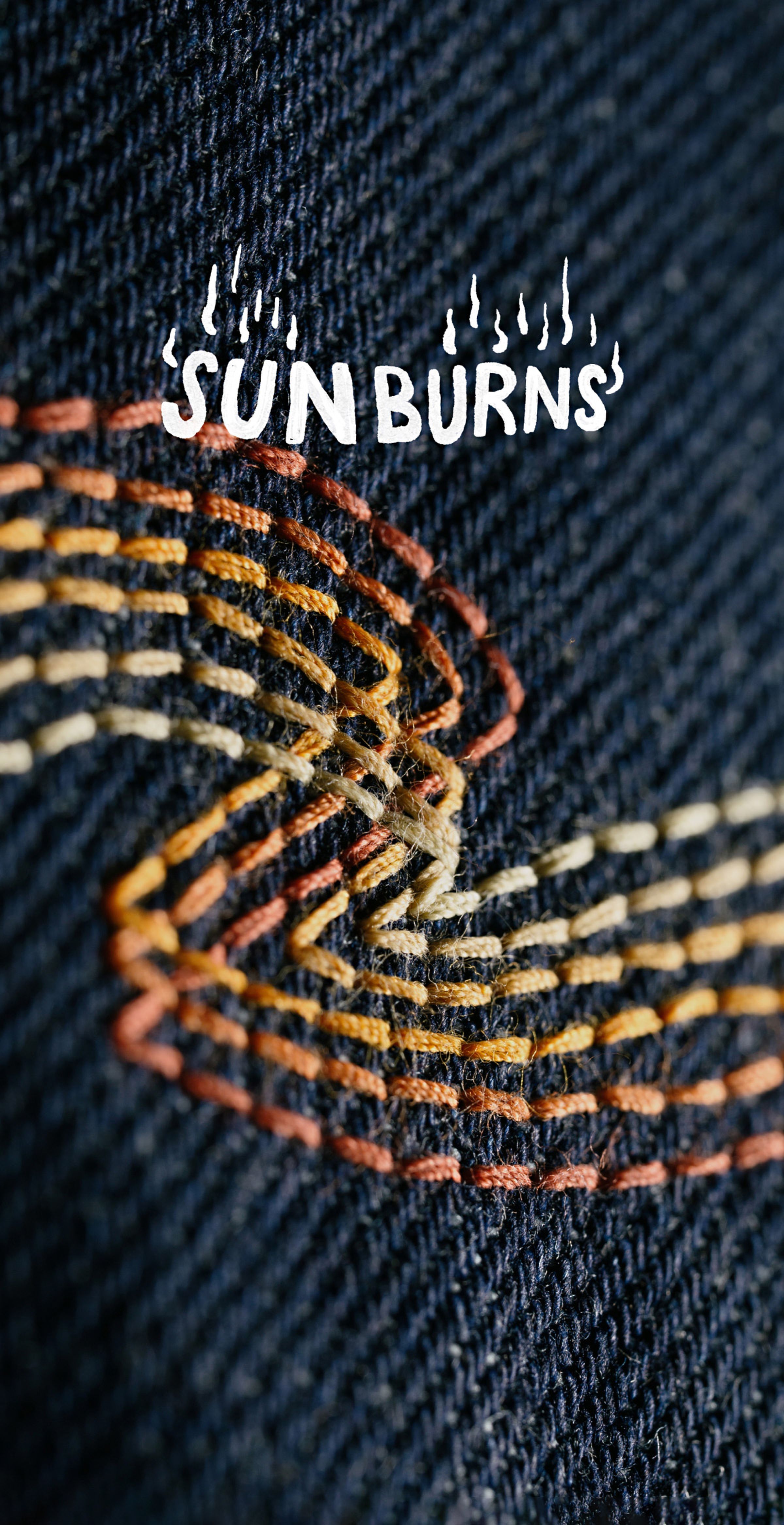 Close-up of colorful embroidery on dark fabric with the word "SUN BURNS" above, featuring a flame-like design.