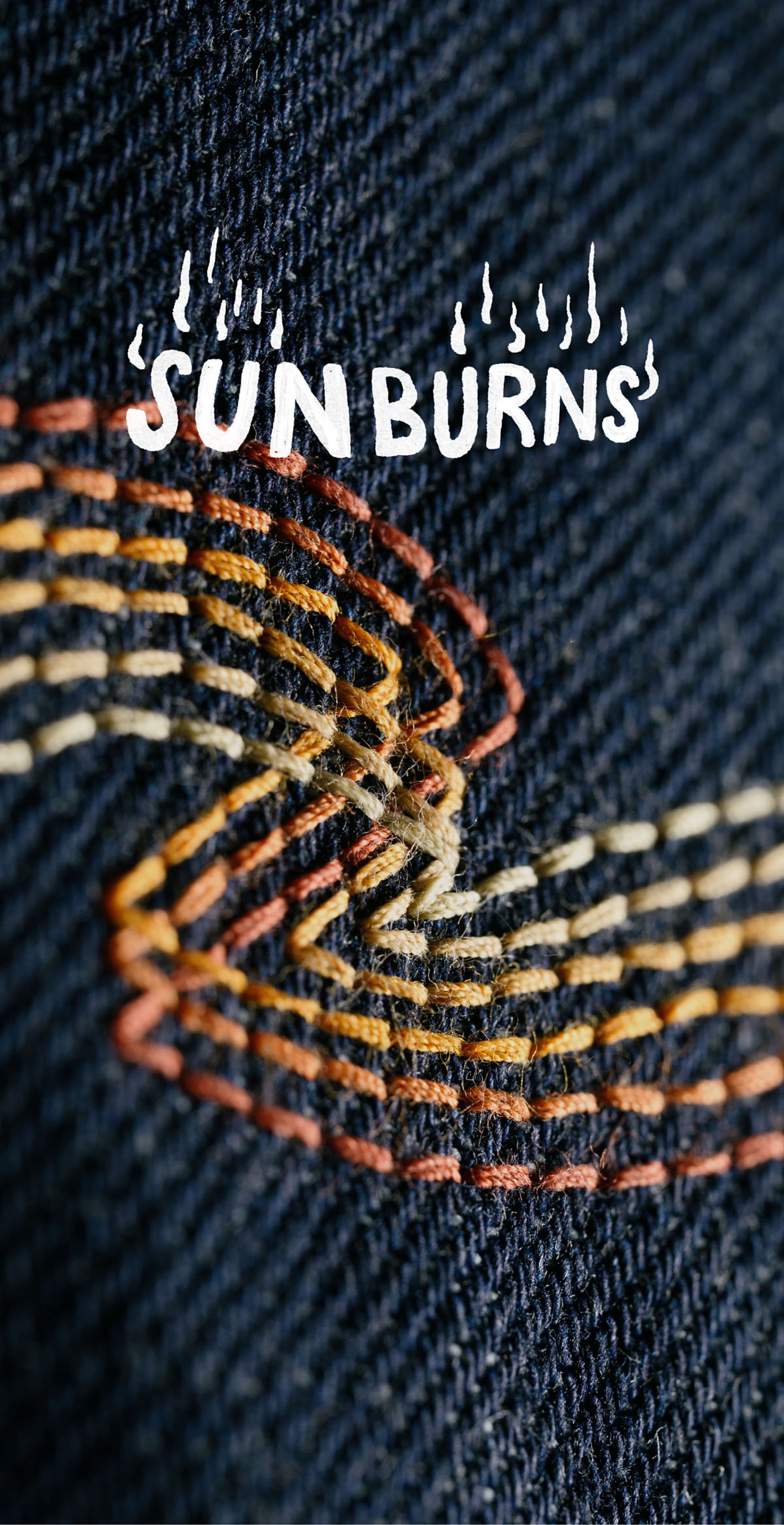 Close-up of colorful embroidery on denim fabric with the text "SUN BURNS" above, featuring stylized flames.