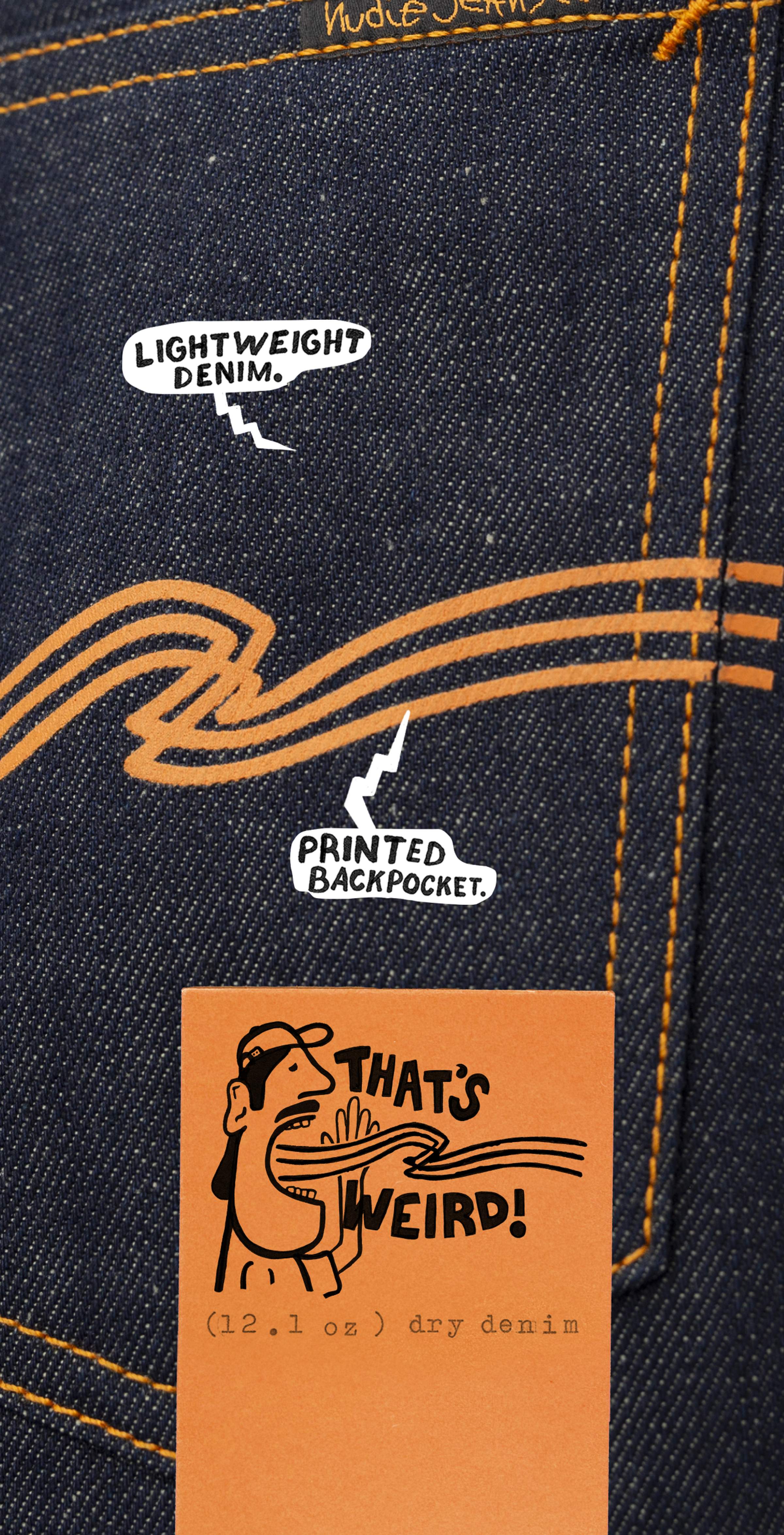 Close-up of dark denim jeans with orange stitching, white text bubbles, and a quirky illustration reading "That's Weird!" on an orange label.