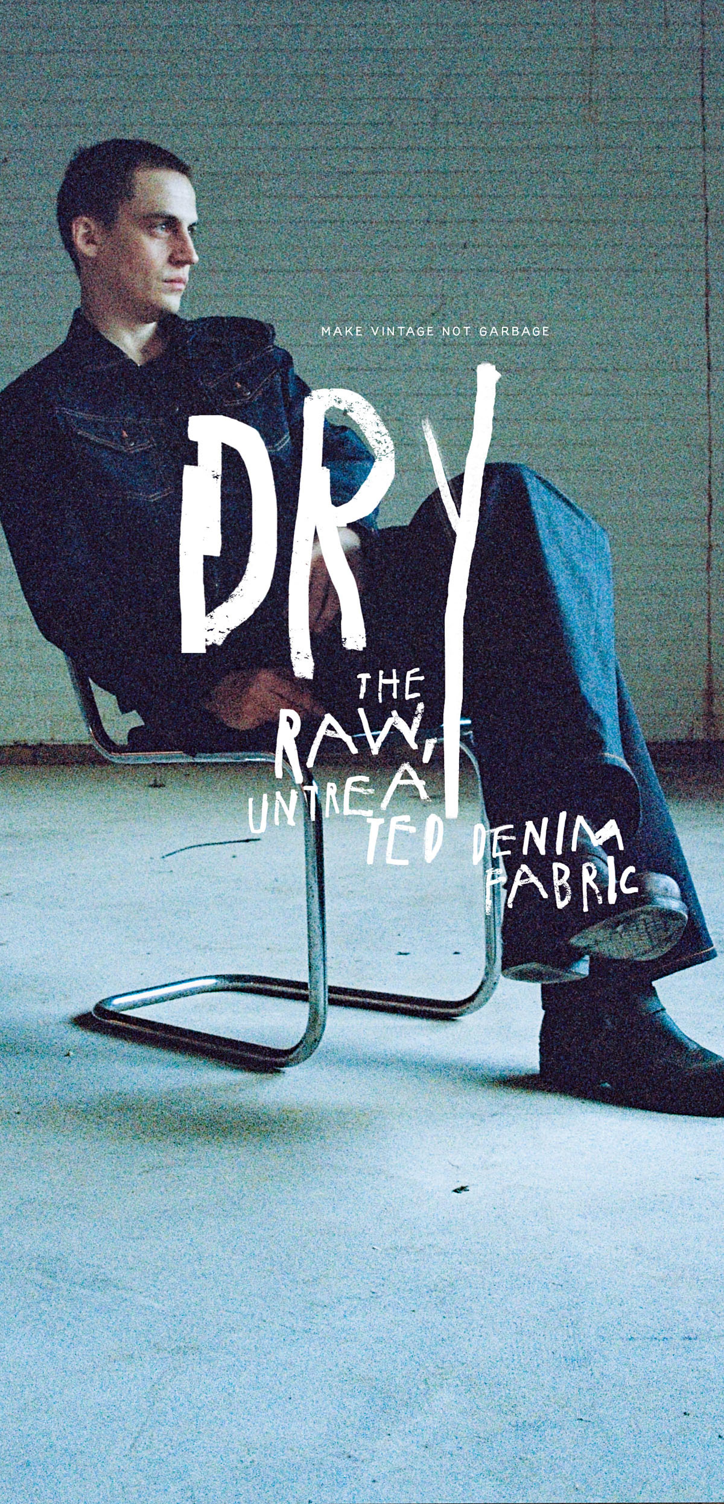 Person seated on a metal chair in a dimly lit room, wearing dark clothing. Text overlay reads "DRY: The Raw, Untreated Denim Fabric."